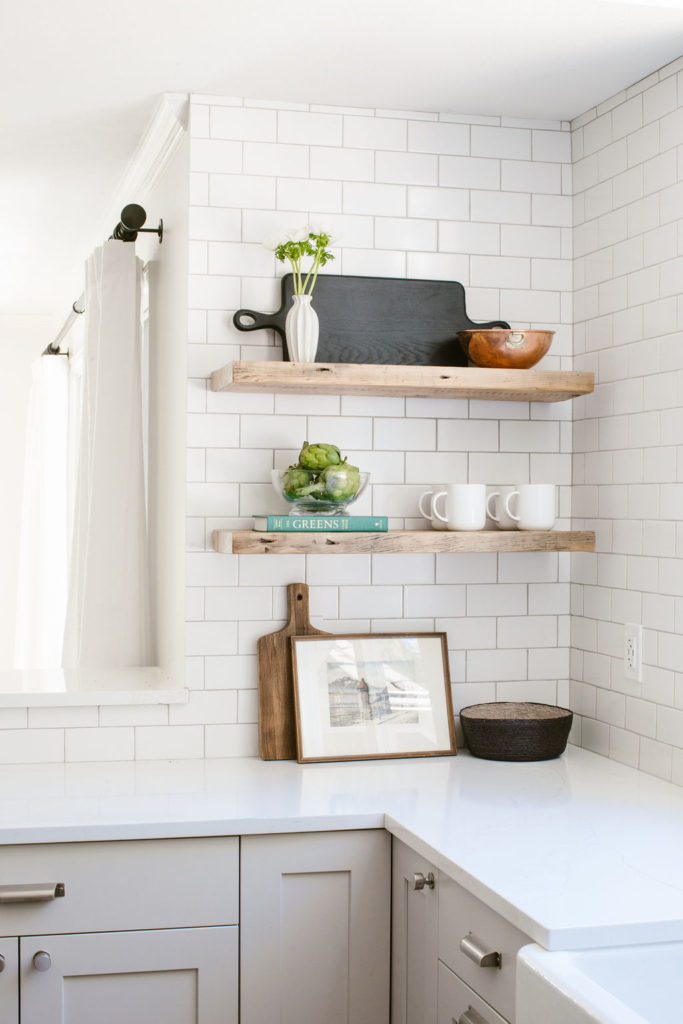 Open shelving in a modern-rustic kitchen with vintage frame, bowls and decor.