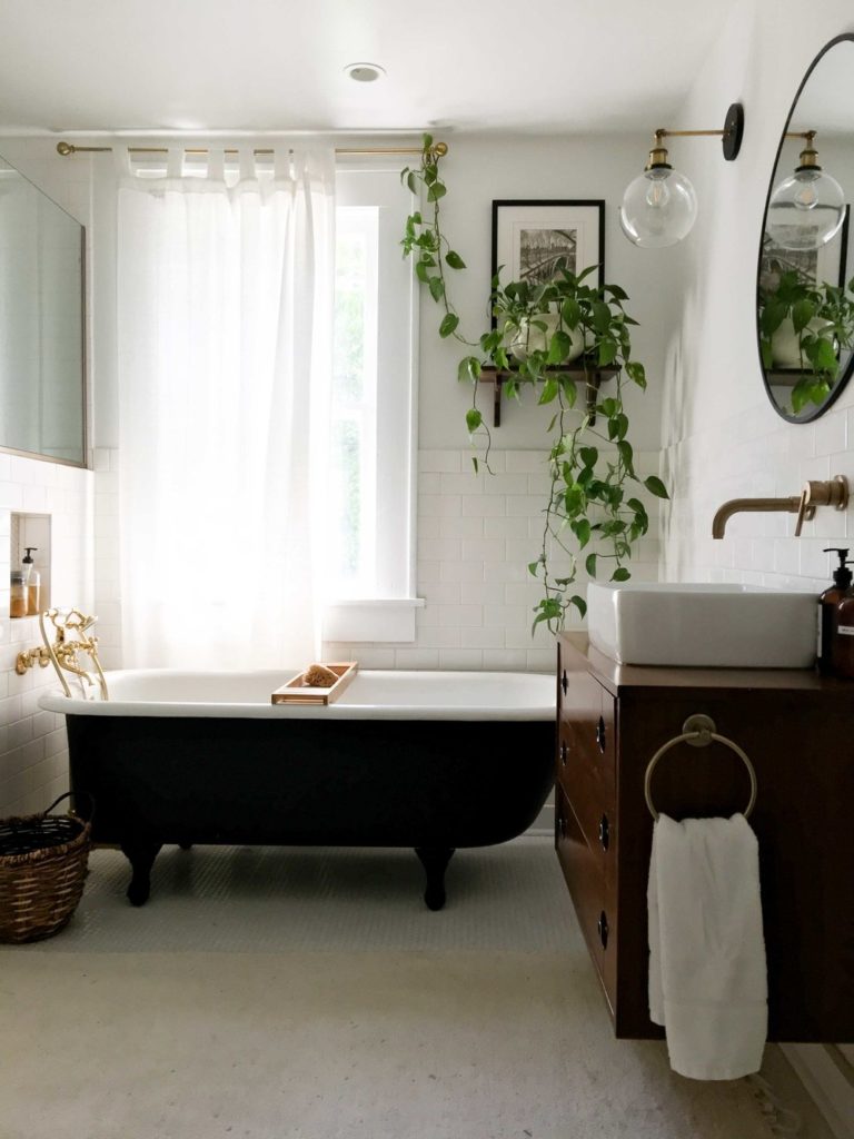 A vintage bathtub and bathroom vanity in a bright, white bathroom.