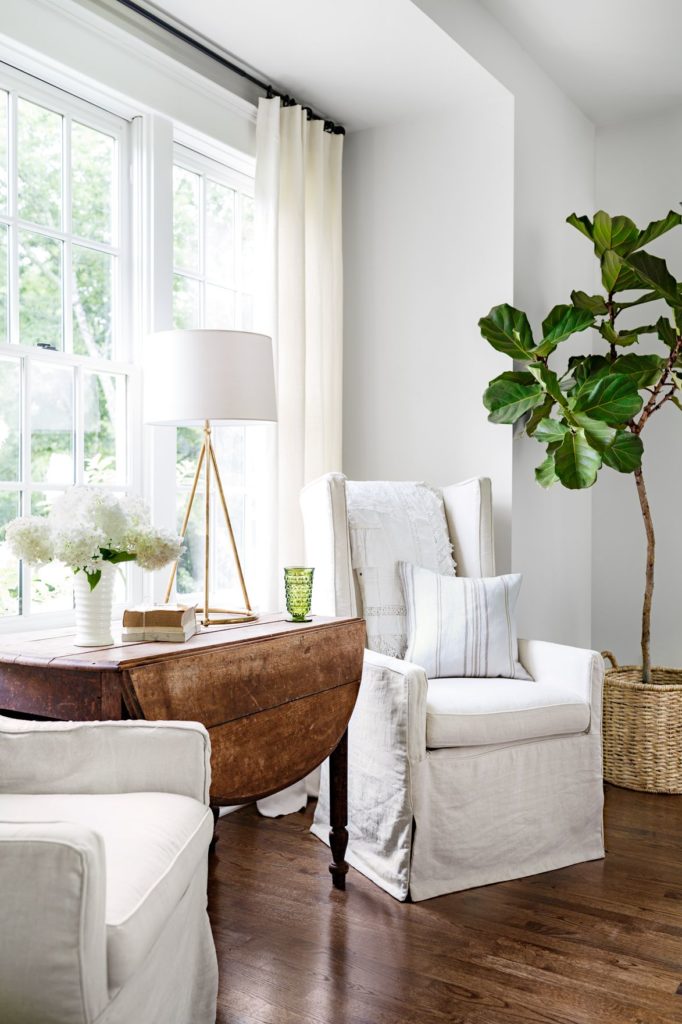 A rustic, drop-leaf antique table in a neutral living room.