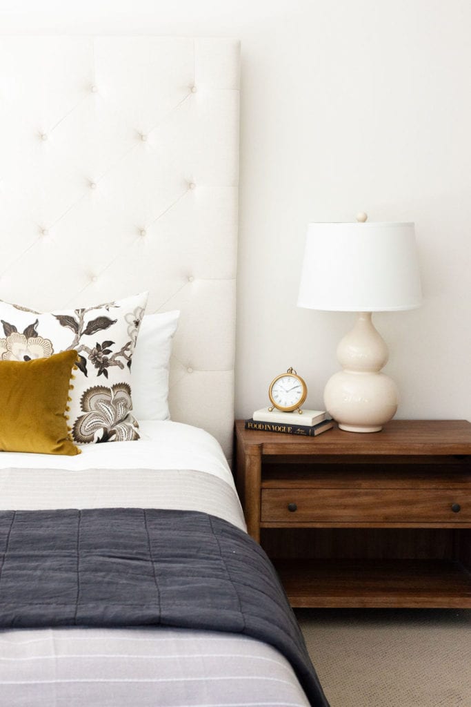 guest bedroom with wood nightstand and linen bedding