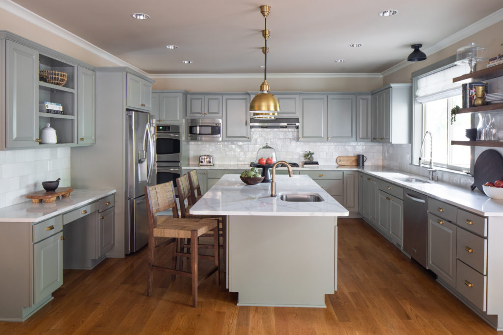 sage green kitchen with gold pendants lights and woven barstools