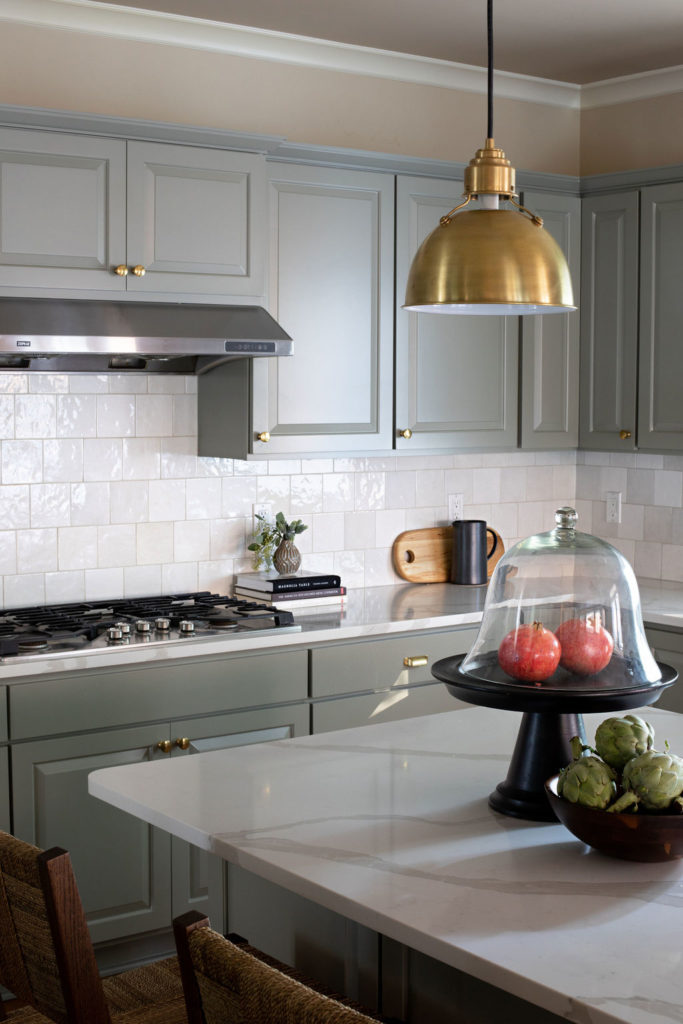 gold pendant lighting in sage green kitchen